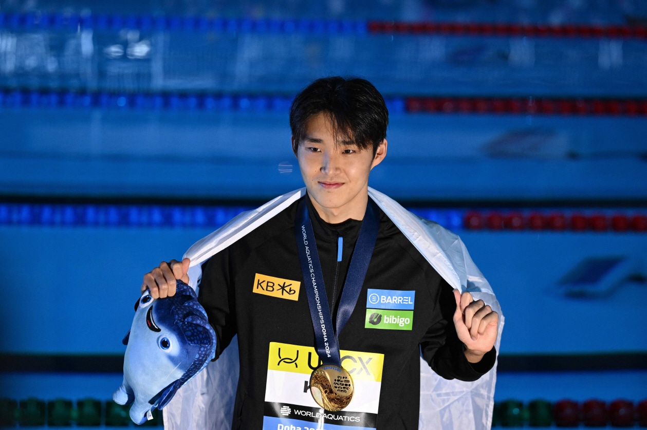 김우민이 12일 카타르 도하 어스파이어돔에서 열린 2024 세계수영선수권대회 남자 자유형 400m에서 우승한 뒤 태극기를 두른 채 기념촬영하고 있다. 김우민은 13년 만에 세계선수권 금메달을 따낸 한국 선수가 됐다. 연합뉴스