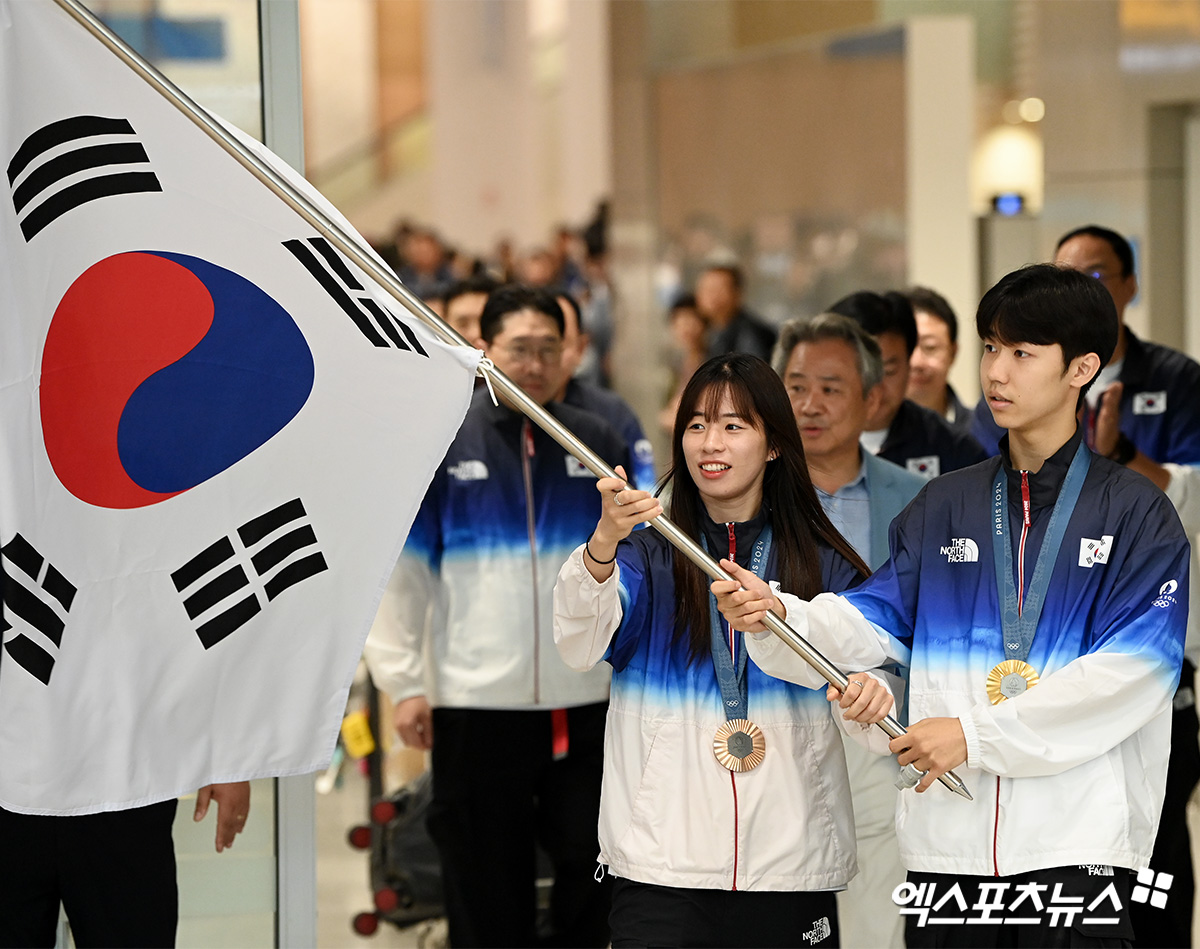 복싱 동메달리스트 임애지, 태권도 금메달리스트 박태준(왼쪽부터)이 13일 인천국제공항을 통해 대한민국 본진 선수단 귀국 때 기수로 입국장에 들어서고 있다. 한국 선수단은 이번 대회에서 20살 안팎의 어린 선수들이 괴력을 발휘하며 깜짝 메달을 쏟아냈다. 한국은 2008 베이징 올림픽, 2012 런던 올림픽에서 기록했던 역대 최대 금메달과 타이를 기록했다. 한국은 금메달 13개, 은메달 9개, 동메달 10개를 획득해 종합 순위 8위로 대회를 마쳤다. 인천공항, 고아라 기자