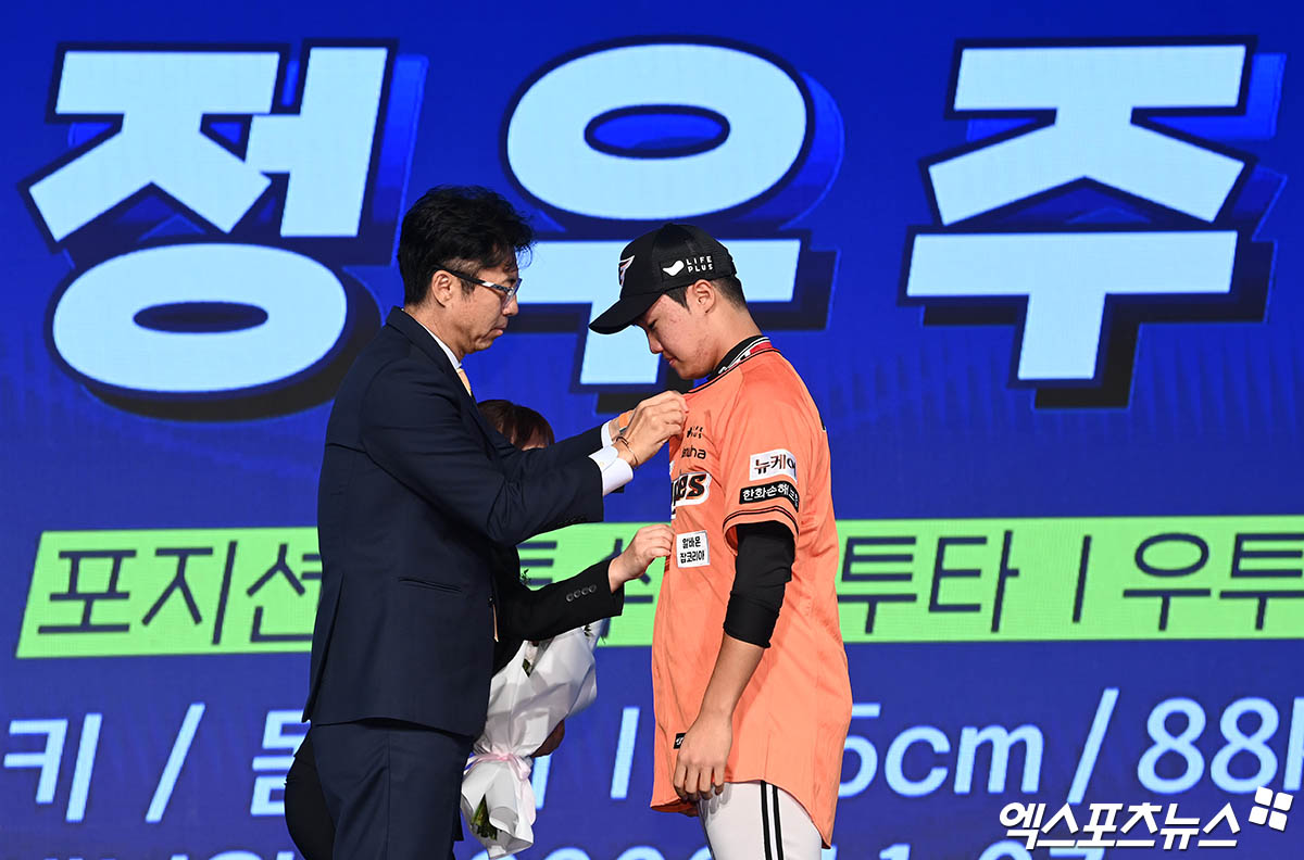 11일 오후 서울 신천동 롯데호텔 월드에서 열린 '2025 KBO 신인 드래프트'에 참석한 한화 손혁 단장이 1라운드 2순위로 전주고 정우주를 지명한 뒤 유니폼을 입혀주고 있다. 엑스포츠뉴스 DB